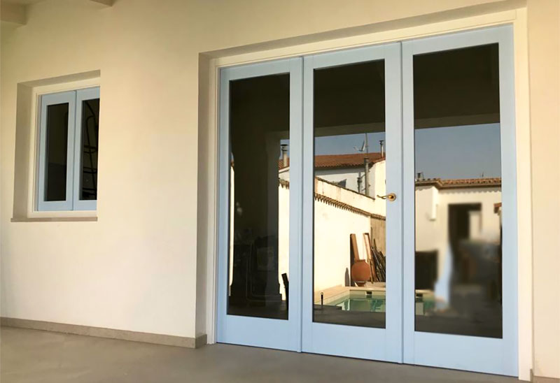 Puerta de madera plegable con doble acristalamiento con acceso a terraza de vivienda.